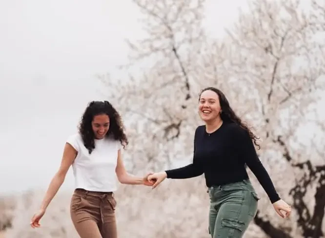 Dos amigas riéndose entre almendros en flor, foto editada