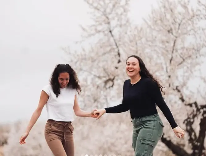Dos amigas riéndose entre almendros en flor, foto editada
